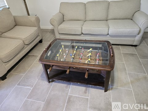 A table with a shuffleboard game on it sits in a living room with two couches.