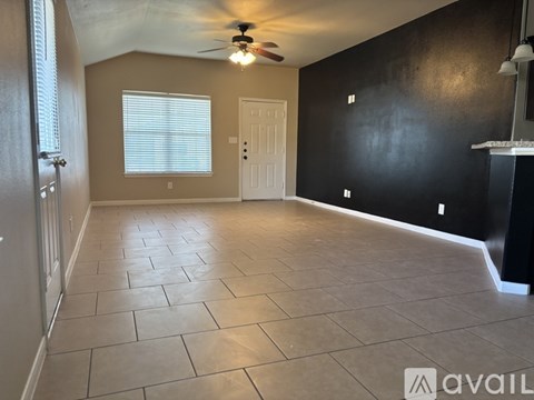 A room with a ceiling fan and tile flooring.
