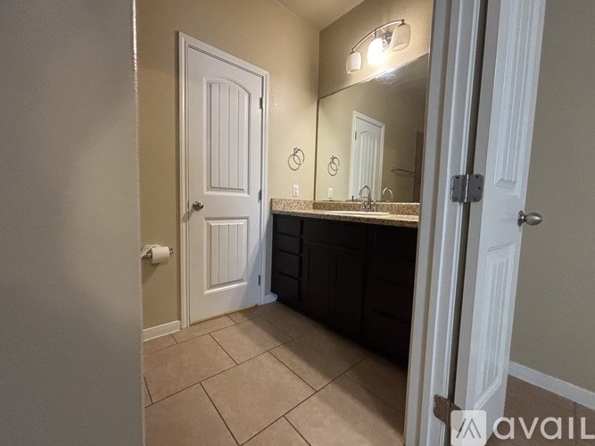 A bathroom with a white door, a mirror, and a sink.