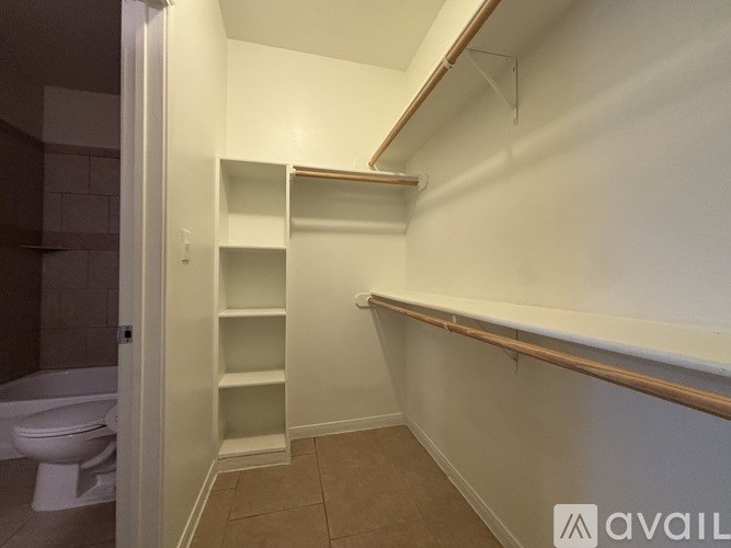 A small white closet with shelves and a toilet visible in the background.