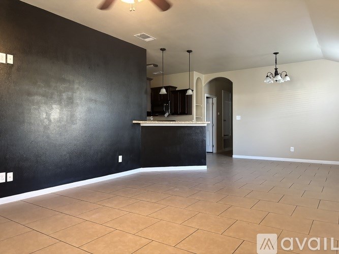 A spacious room with a kitchenette and a ceiling fan.