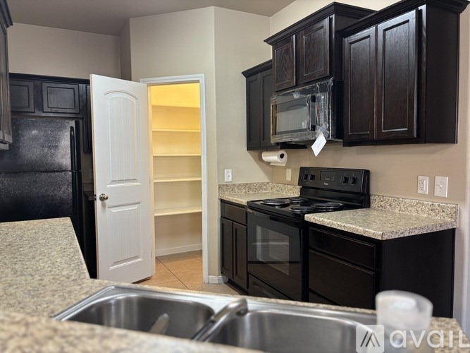 A kitchen with black cabinets and a white door.