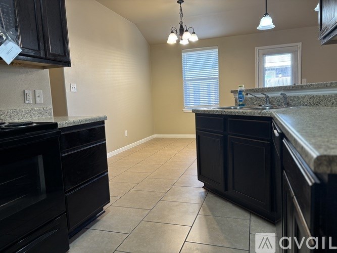 A kitchen with black cabinets and a granite countertop.