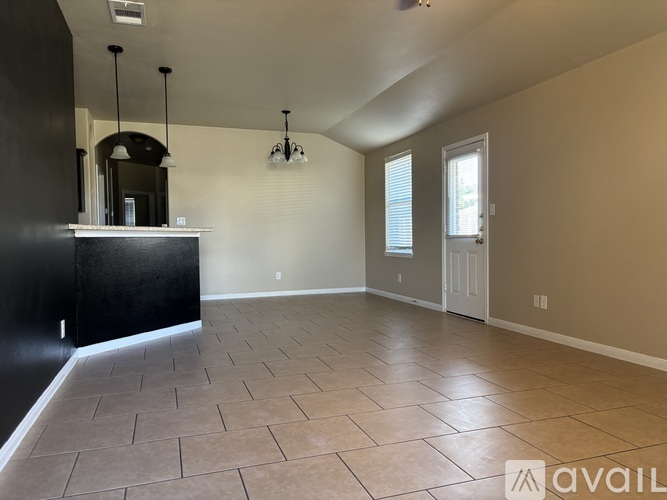 A spacious room with a black counter and tiled floor.