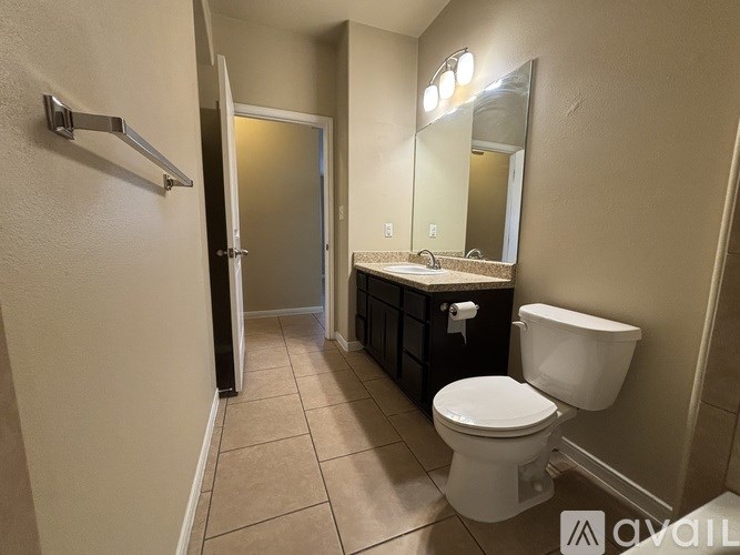 A bathroom with a toilet, sink, and mirror.
