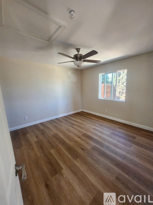 A room with a ceiling fan and wooden flooring.