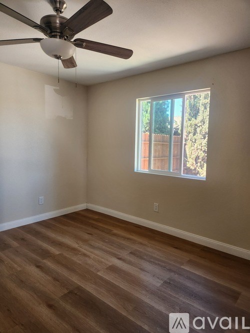 A room with a ceiling fan and wooden flooring.