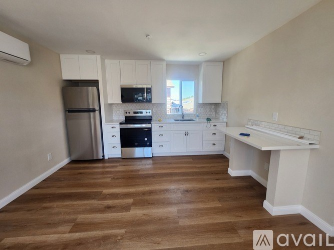 A kitchen with wooden floors and white cabinets.