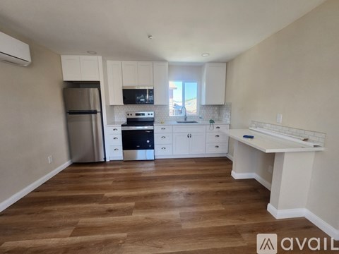 A kitchen with wooden floors and white cabinets.