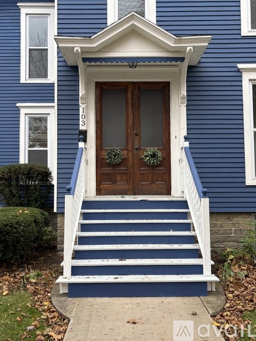 A blue house with a brown door and a wreath on it.