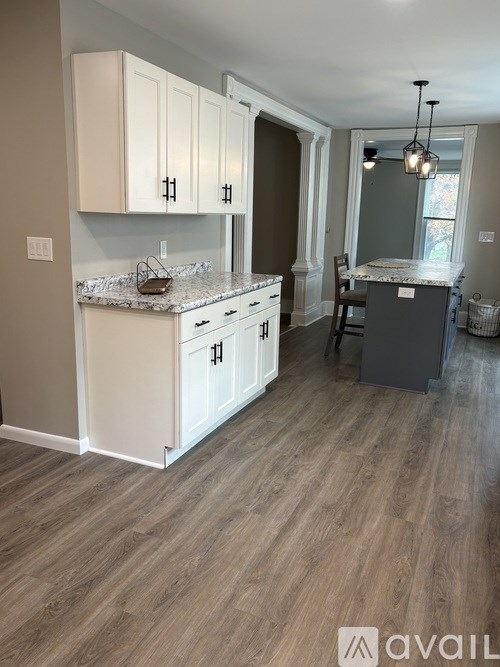 A kitchen with white cabinets and a marble countertop.