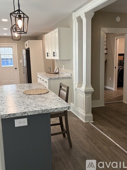 A kitchen with a marble countertop and a grey island.