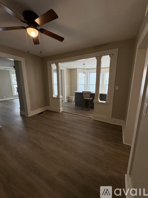 A spacious room with a ceiling fan and wooden flooring.