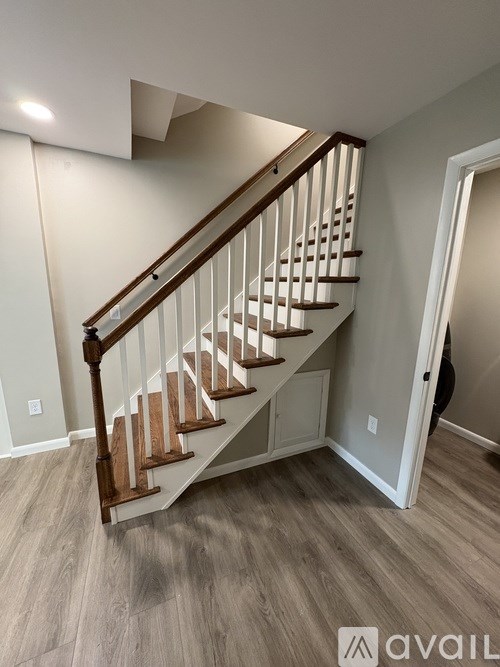 A wooden staircase with a light brown finish and white walls.