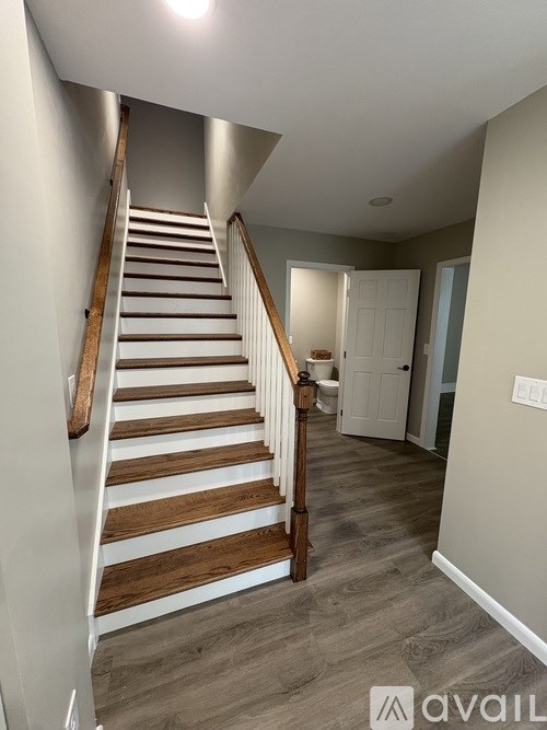 A staircase with wooden steps and white railings leads up to a doorway.