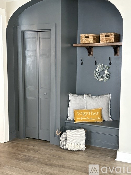 A grey door with a wreath and a pillow that says "together" on a bench.