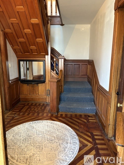 A wooden staircase with a carpeted runner leads up to a landing with a mirror and a door.