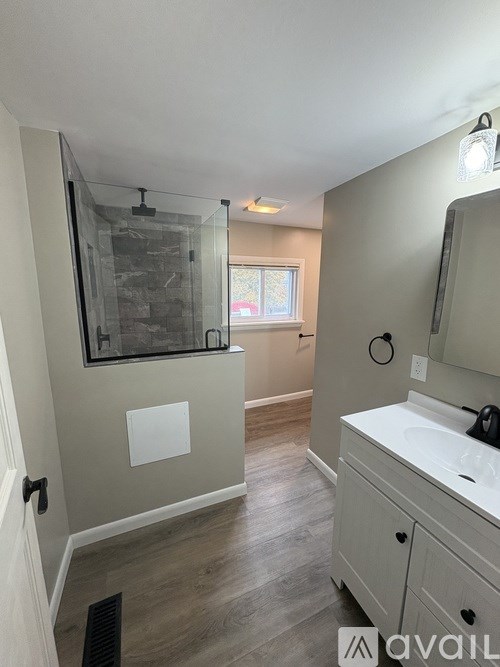 A bathroom with a sink, mirror, and a glass shower door.
