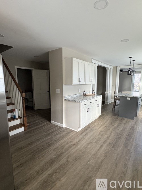 A kitchen with white cabinets and a wooden floor.