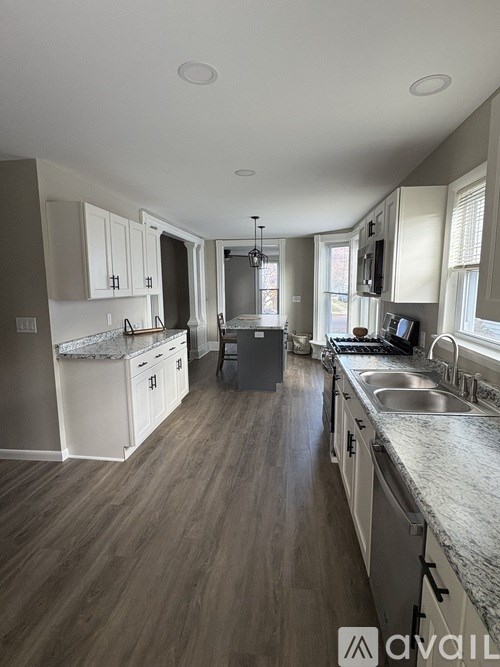 A kitchen with white cabinets and a marble countertop.