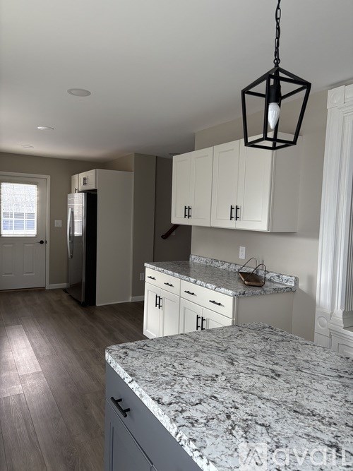 A kitchen with a marble countertop and white cabinets.