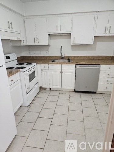 A kitchen with white appliances and cabinets.