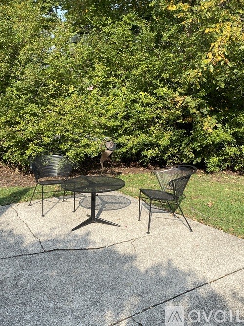 A glass table and two chairs are set up on a patio.