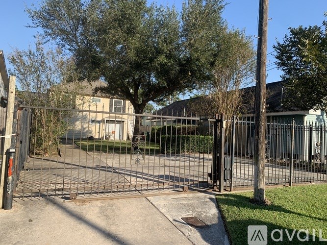 A gated entrance to a property with a large tree in the background.