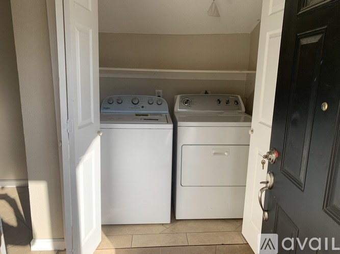 A black door is open to a laundry room with two washing machines.