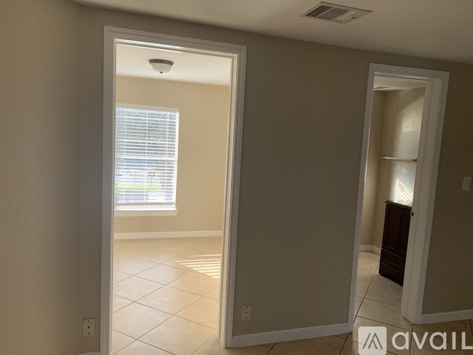 A room with a doorway leading to another room with a window.