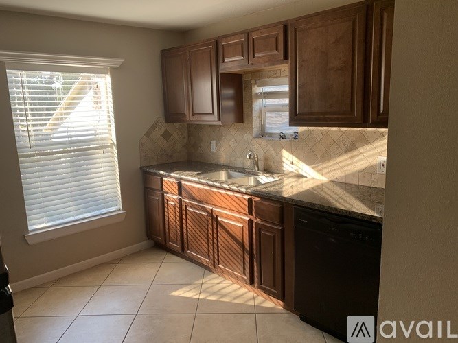 A kitchen with brown cabinets and a black dishwasher.