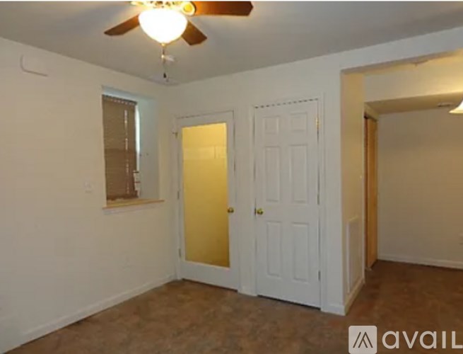 A room with a ceiling fan and two doors.