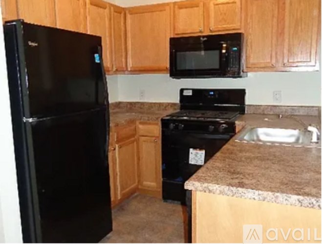 A kitchen with black appliances and wooden cabinets.