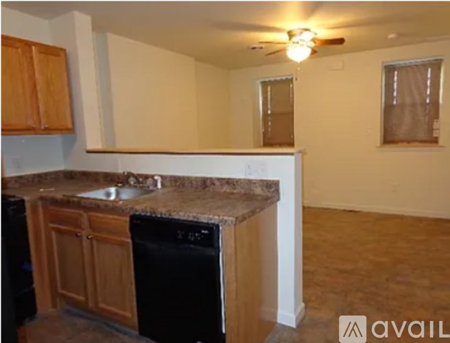 A kitchen with a black dishwasher and wooden cabinets.