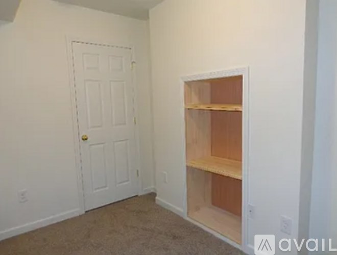 A room with a door and a shelf built into the wall.