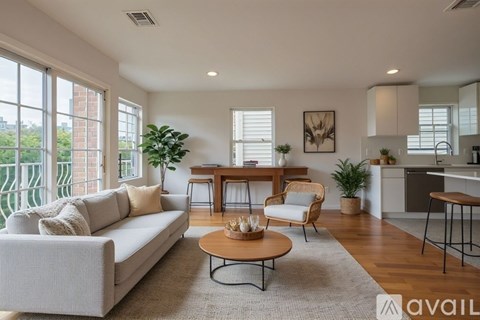 A living room with a white couch, a wooden coffee table, and a dining area in the background.