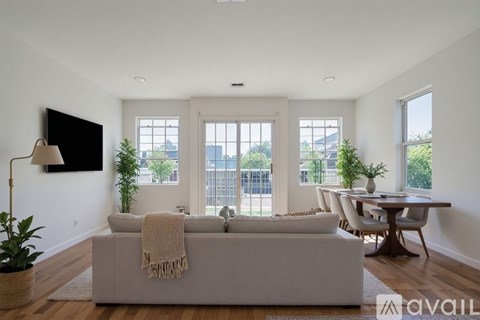 A living room with a grey couch and a flat screen TV mounted on the wall.
