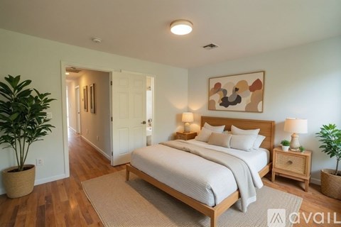 A bedroom with a large bed, two lamps, and a painting on the wall.