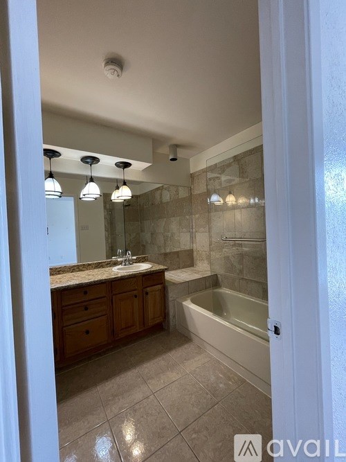 A bathroom with a tub, sink, and mirror.