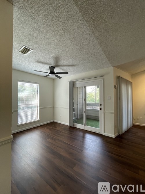 A room with a ceiling fan and sliding glass doors.