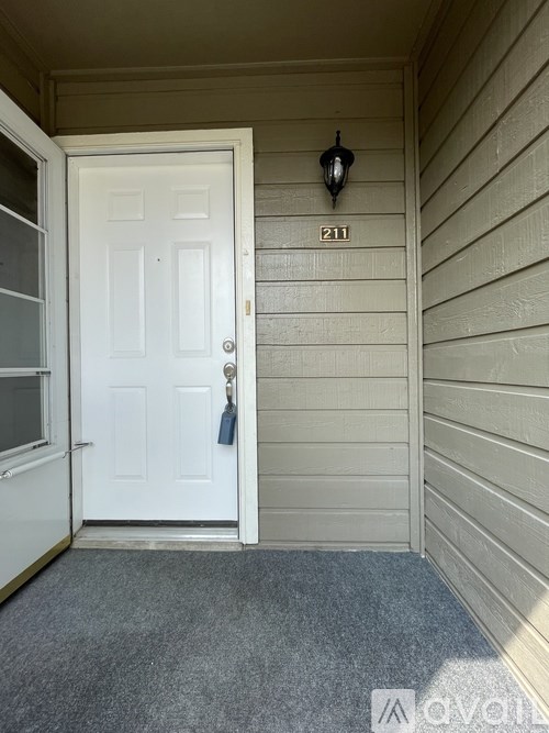 A white door with a black handle and a black lantern on the wall above it.