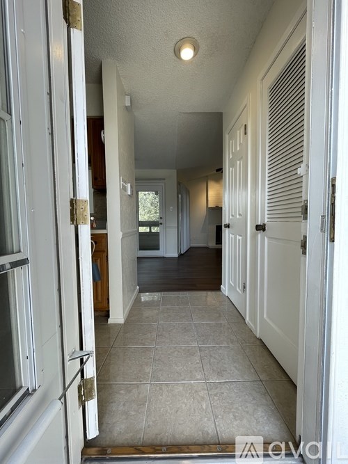 A long hallway with white doors and tiled floors.