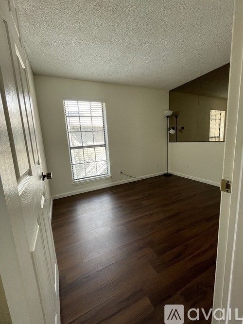 A room with wooden floors and a window with blinds.