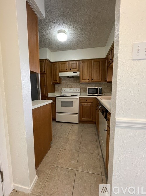 A kitchen with a white stove and wooden cabinets.