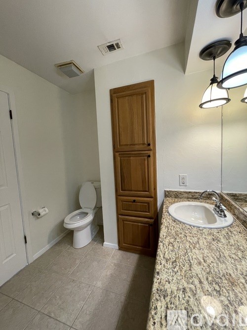 A bathroom with a toilet, sink, and wooden door.