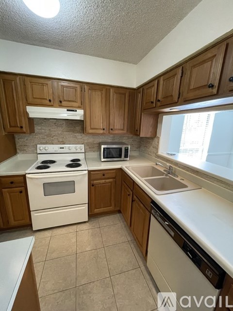 A kitchen with a white stove and wooden cabinets.