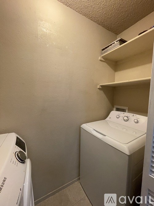 A white dryer is on the left of a white washing machine in a small laundry room.