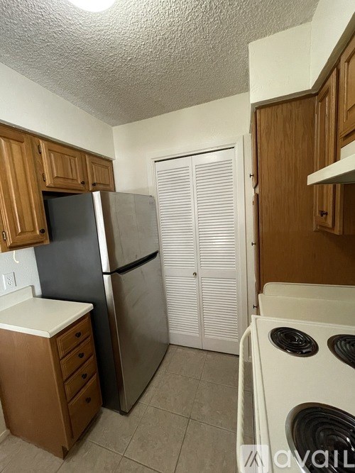A kitchen with a black fridge, white stove and wooden cabinets.