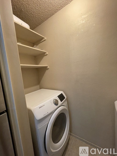 A small white washing machine sits in a laundry room.