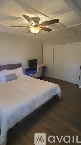 A bedroom with a bed, a ceiling fan, and a television.